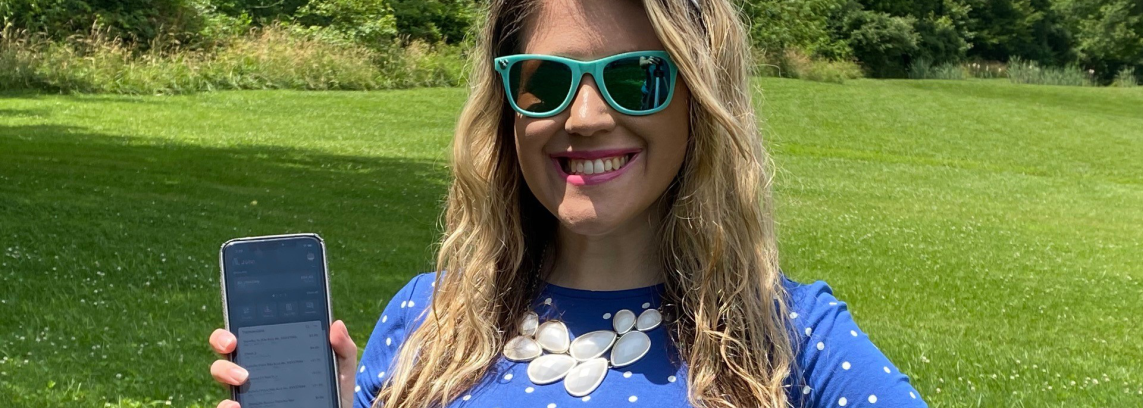 young woman wearing sunglasses and holding up a smartphone