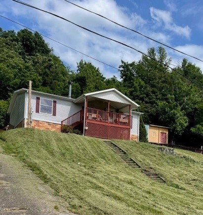 image of manufactured home on a hill. the house has a wooden porch on the front.