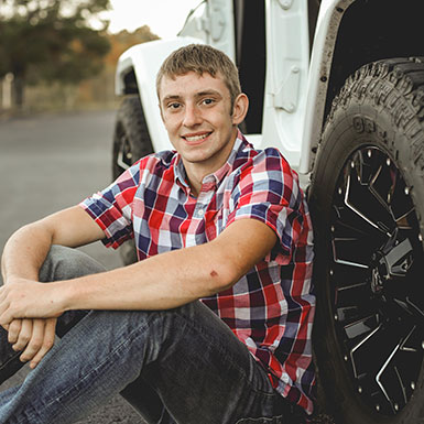 Young man leaning against his jeep