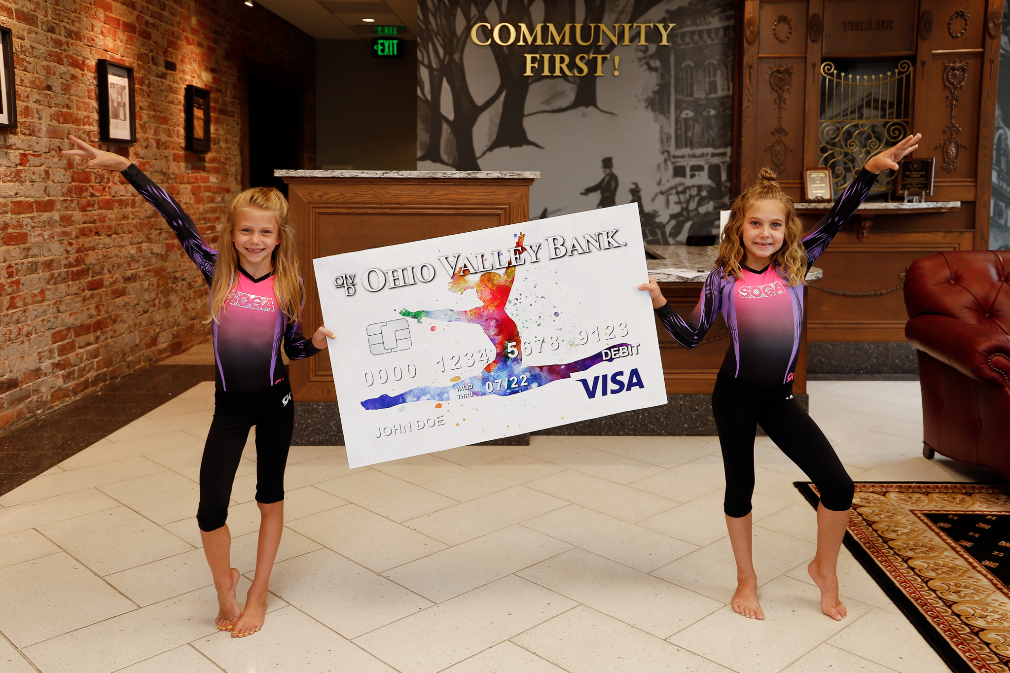 two young gymnasts posing with oversized debit card