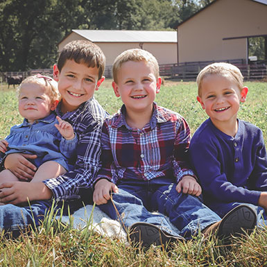 Four young kids posing for photographs in a yard